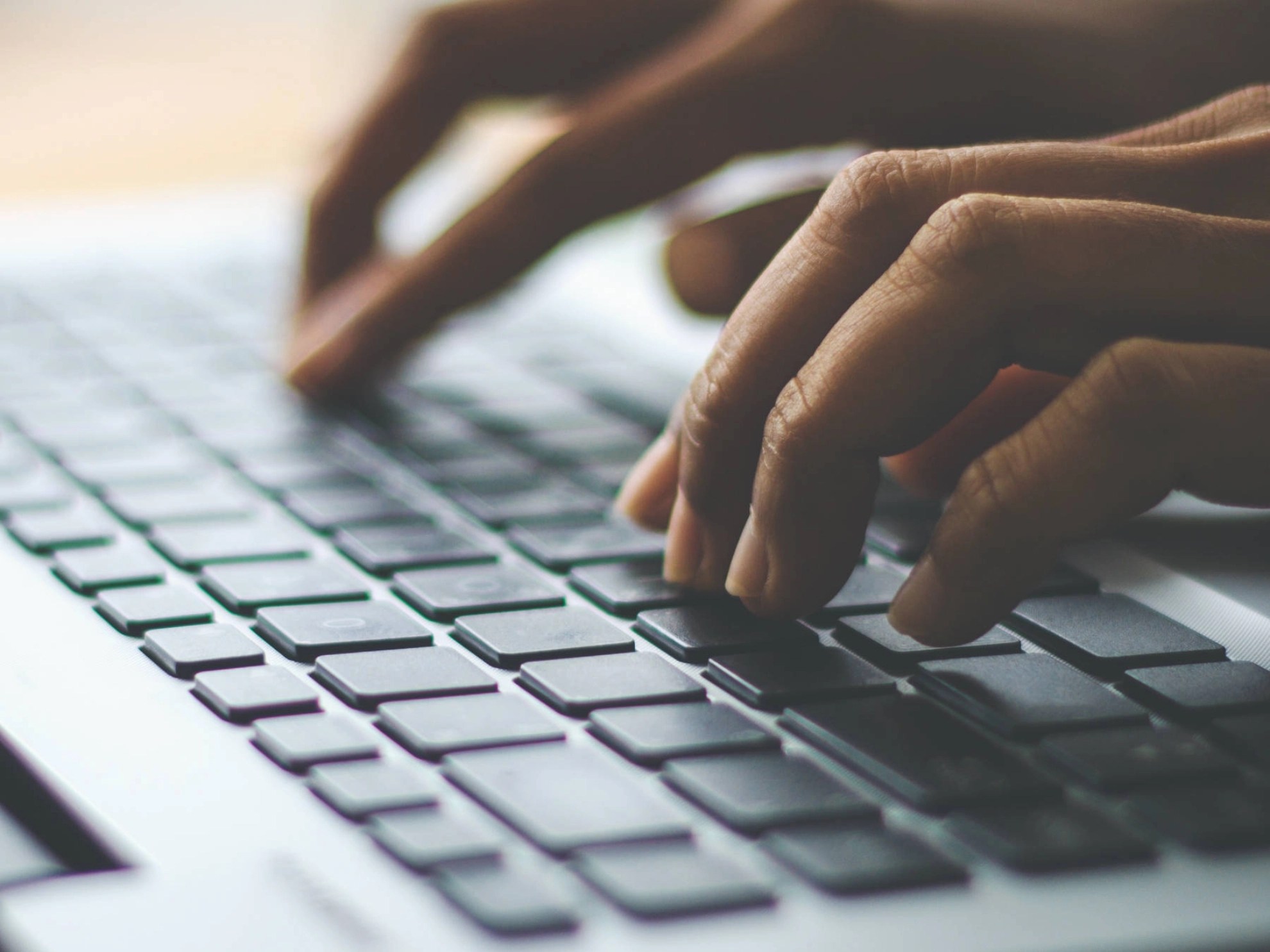 Hände, die auf einer Tastatur tippen.