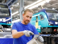 Ein Mitarbeiter feilt ein Metallteil beim Hersteller von Schienenfahrzeugen Stadler in Berlin